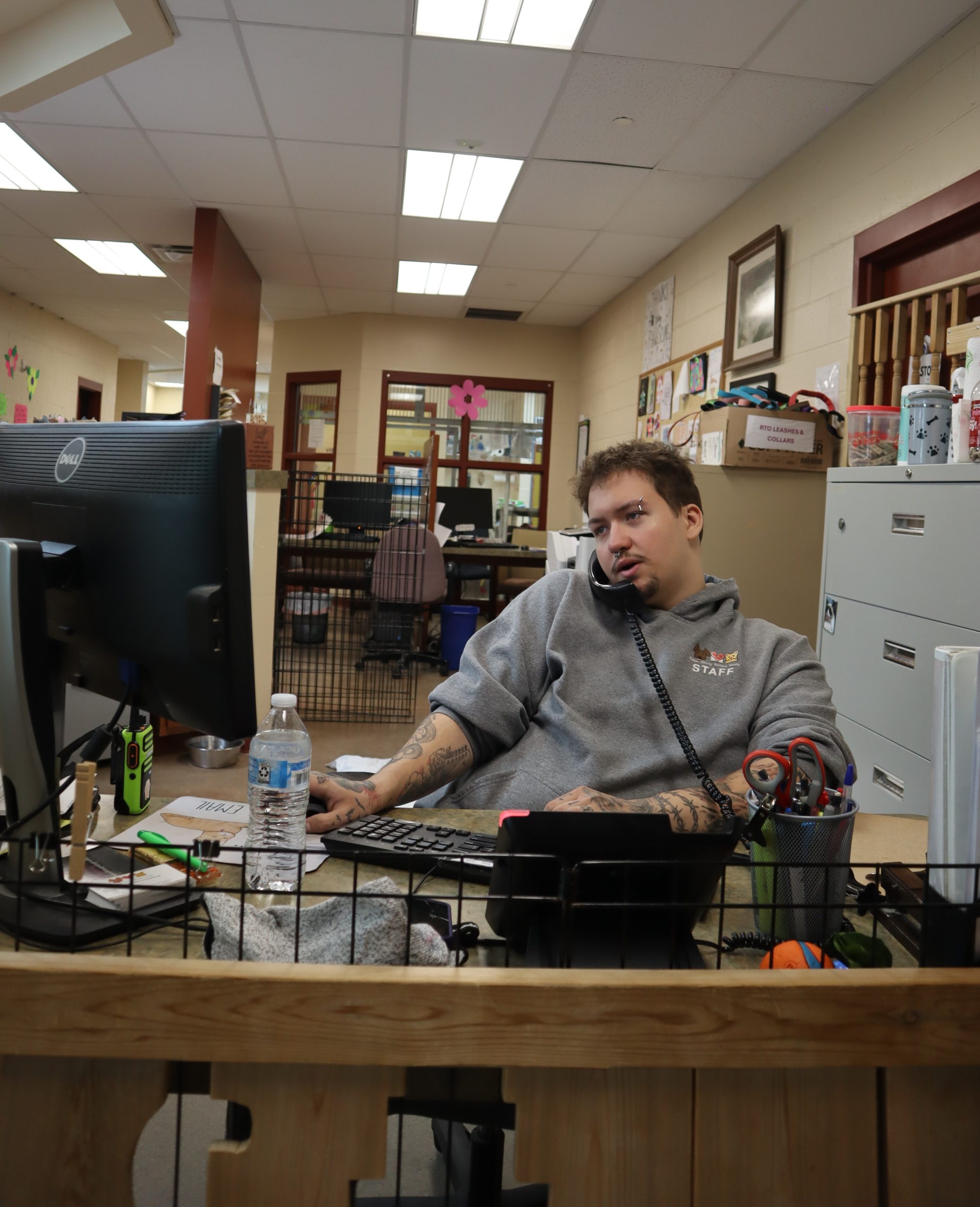 Man sitting at front desk with a corded phone against his ear.